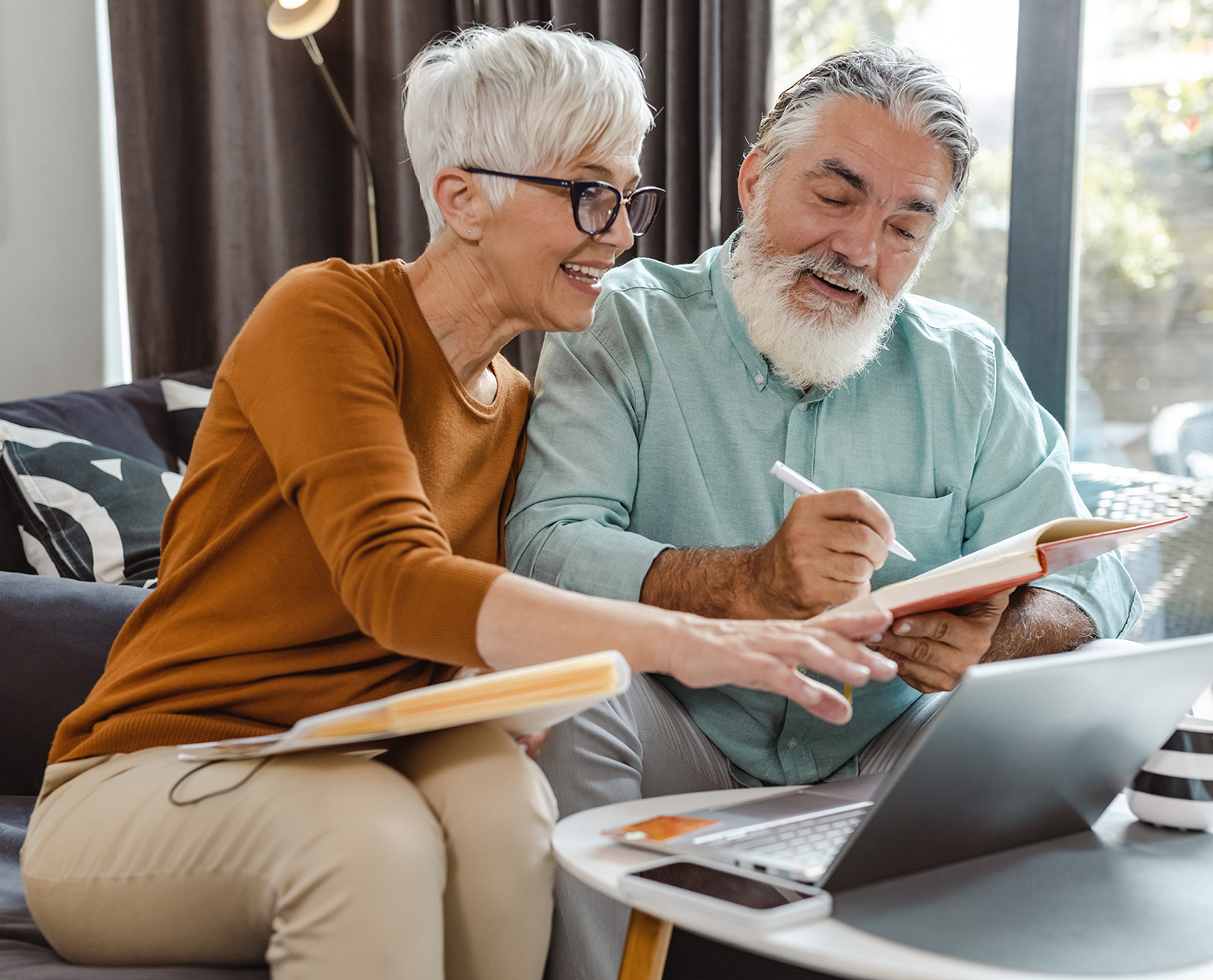 Couple sitting on a couch looking at paperwork.