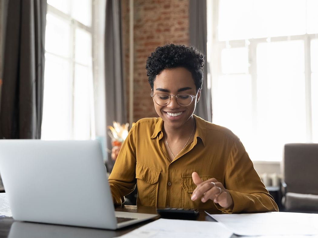 A woman sits at her laptop.
