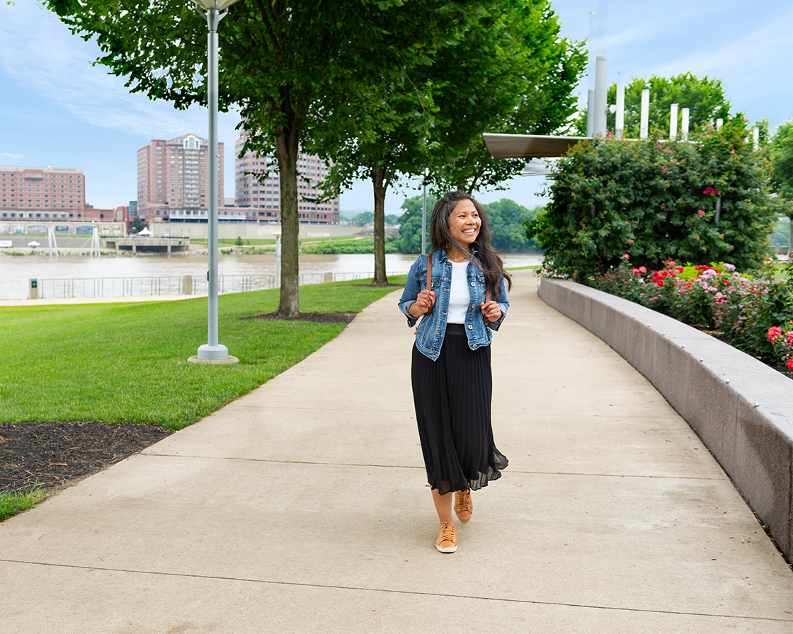 Girl walking on the banks with Northern Kentucky behind her.