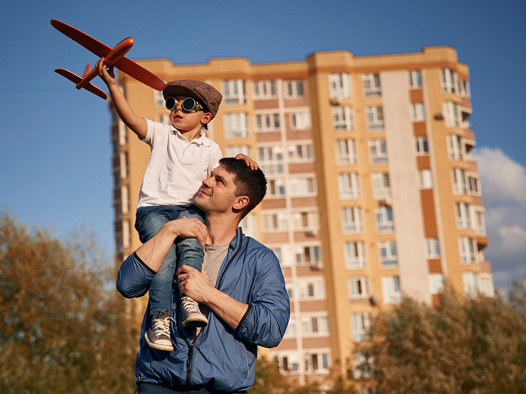 Boy flying toy plane in front of apartments