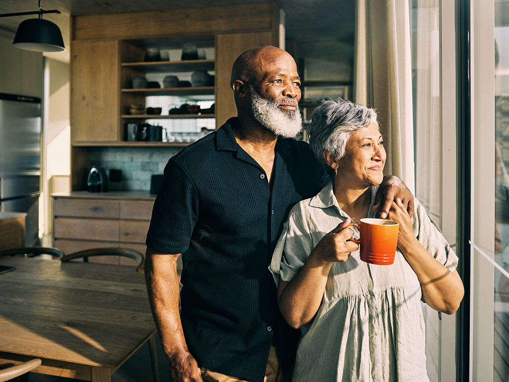 Older couple standing in a very nice kitchen.